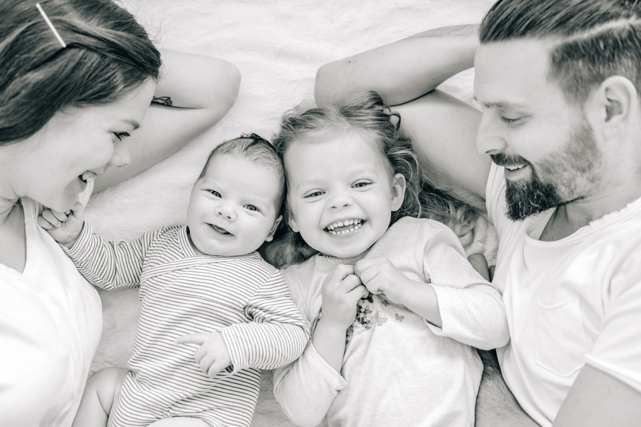 Mama Papa und zwei Kinder kuscheln im Bett bei Baby Homestory